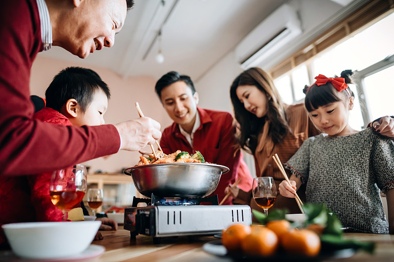 低角度观看三代快乐的亚洲家庭庆祝中国新年和享受美味的传统中国汤菜团圆饭图片下载