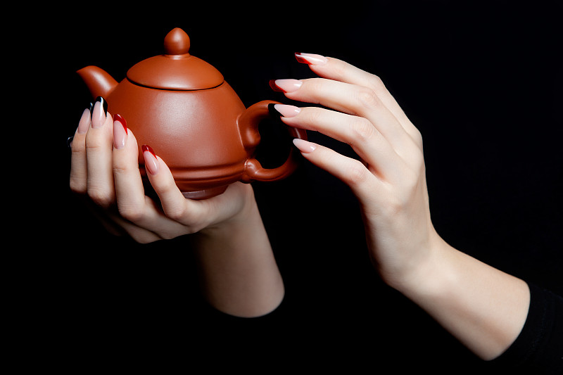 手里拿着一个带盖的日本陶瓷茶壶图片下载