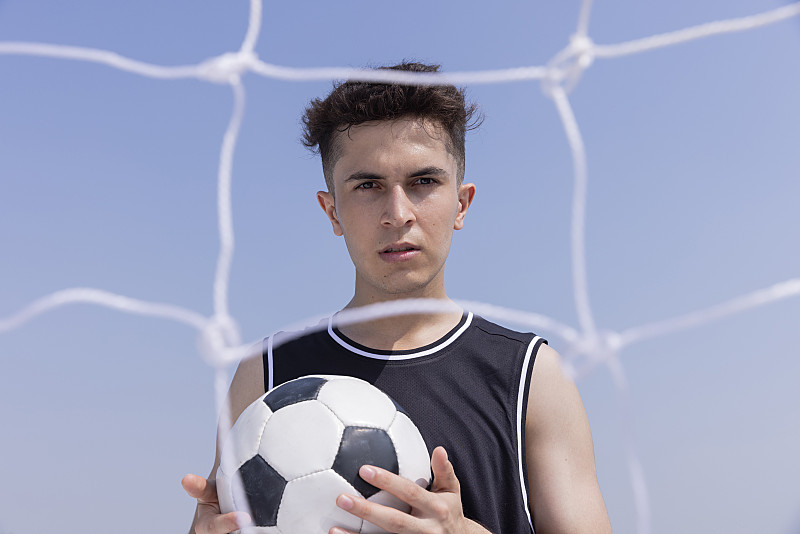 一个年轻人的肖像拿着一个足球与网在前景图片下载