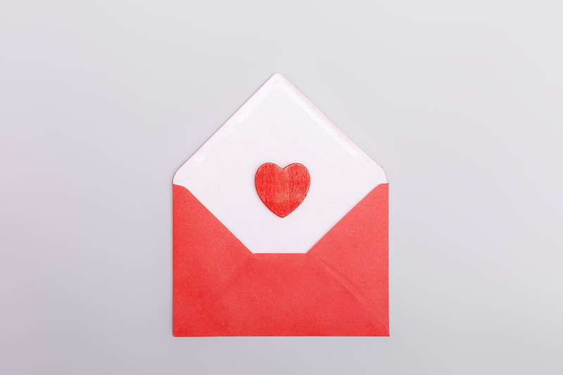 灰色背景下的红包和爱心。情人节的概念，爱情，约会和婚礼。情书的象征。图片下载