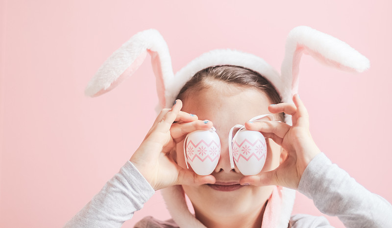 美丽的白人女孩与发带复活节兔子耳朵持有两个复活节彩蛋在眼睛水平图片下载