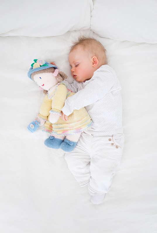 抱着毛绒娃娃睡觉的婴儿图片素材