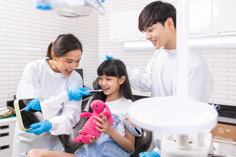 快乐的女牙医和女病人在诊所。亚洲儿童牙科，健康牙齿，美丽笑容。图片下载