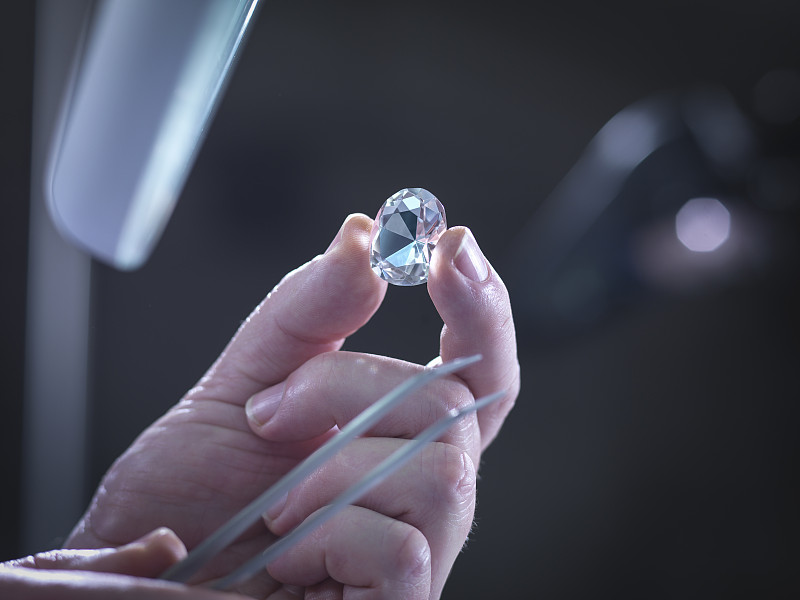Jeweller inspecting replica diamonds in hand图片素材