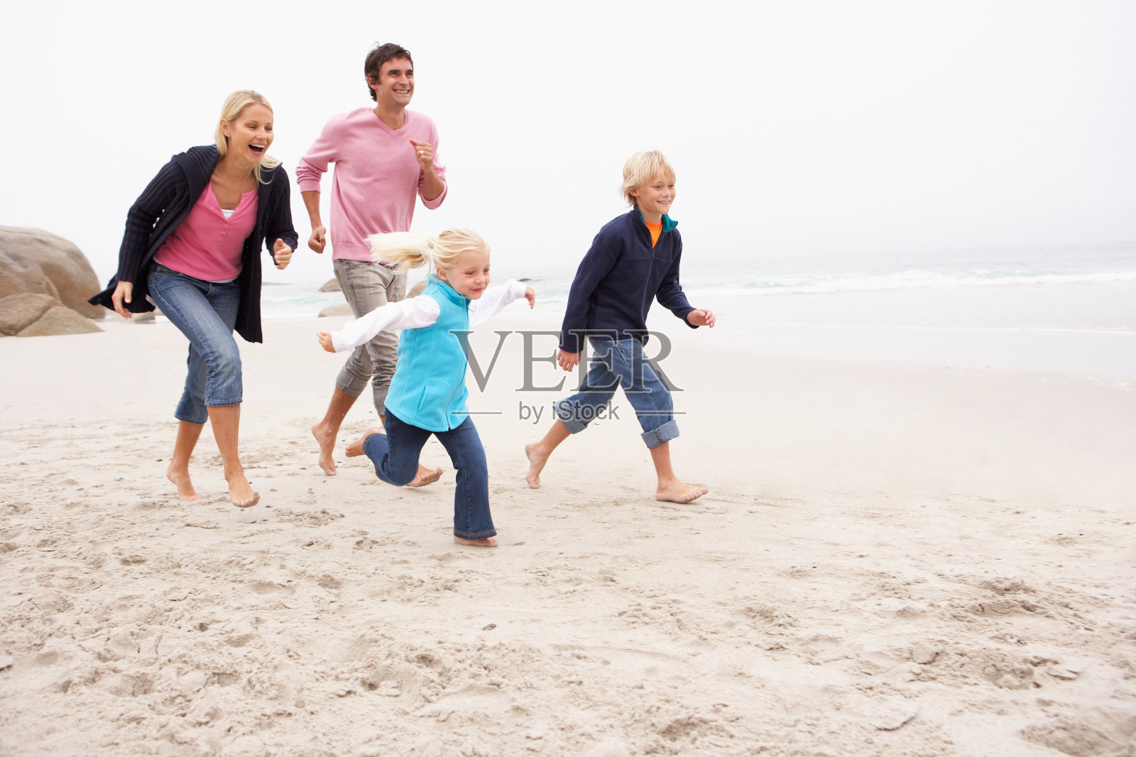 年轻的家庭在冬季海滩上跑步照片摄影图片