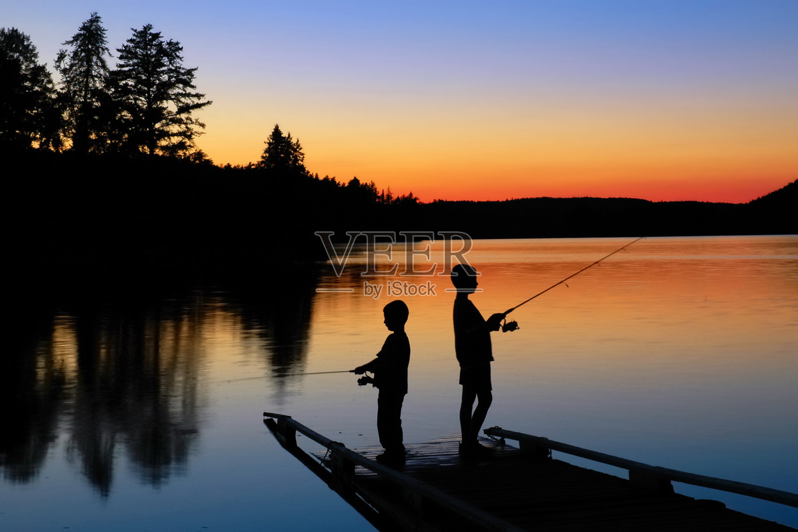 男孩在日落钓鱼照片摄影图片