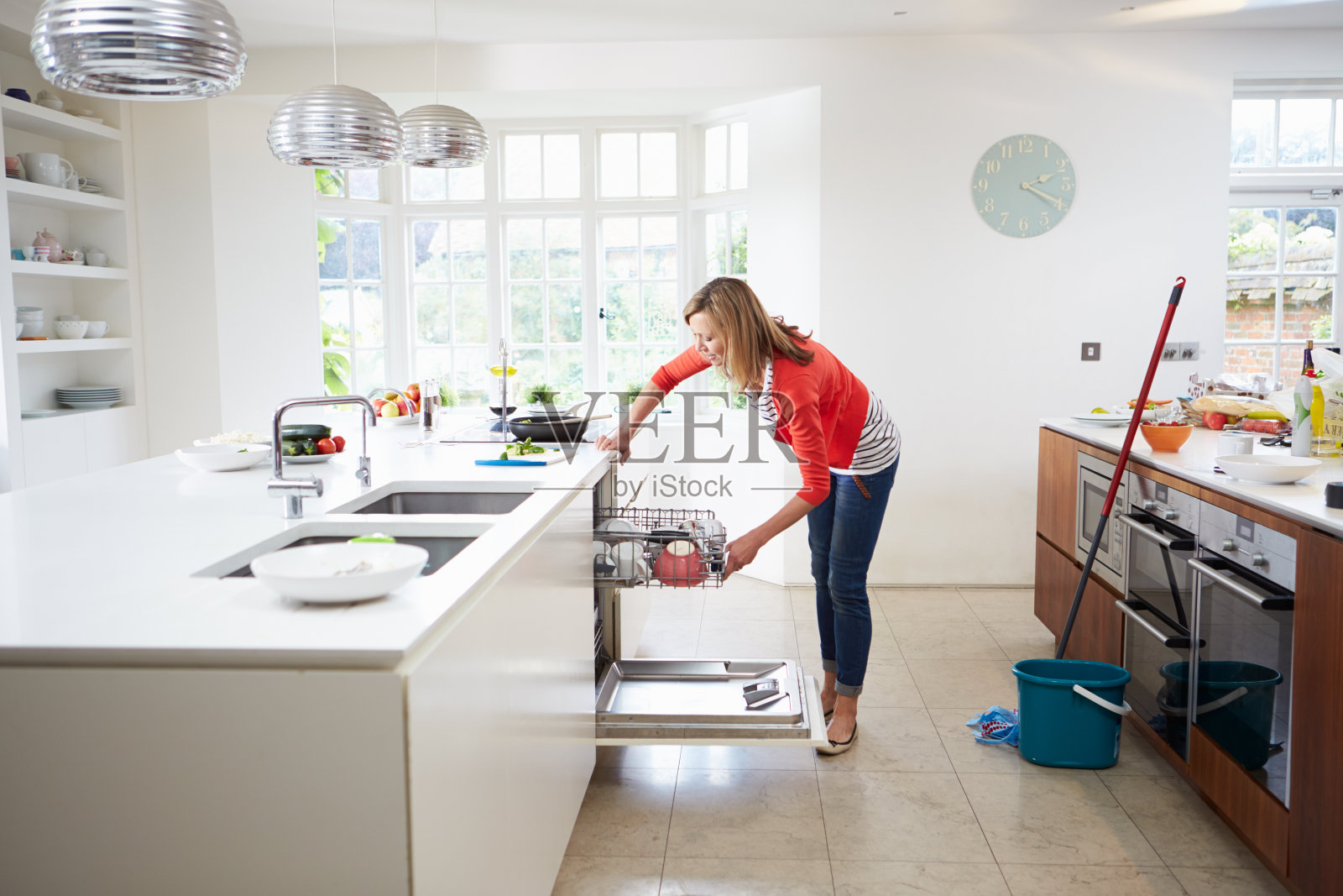 妇女在清洁厨房时将盘子放入洗碗机照片摄影图片