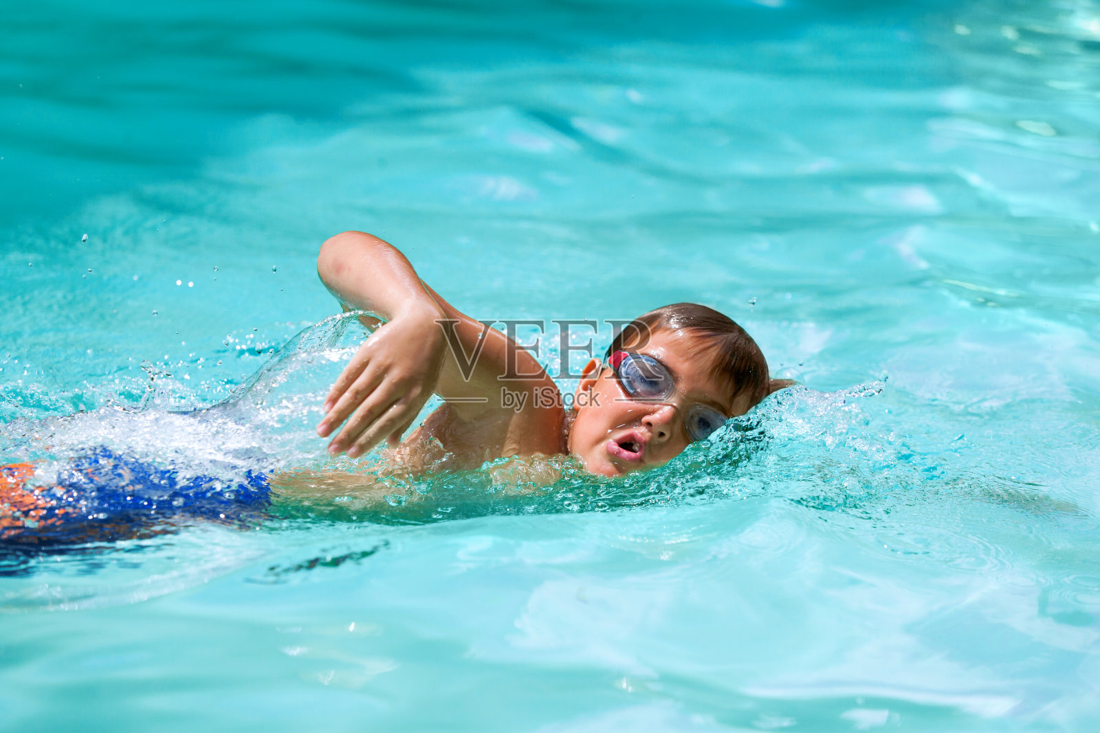 男孩在游泳池里练习自由泳。照片摄影图片