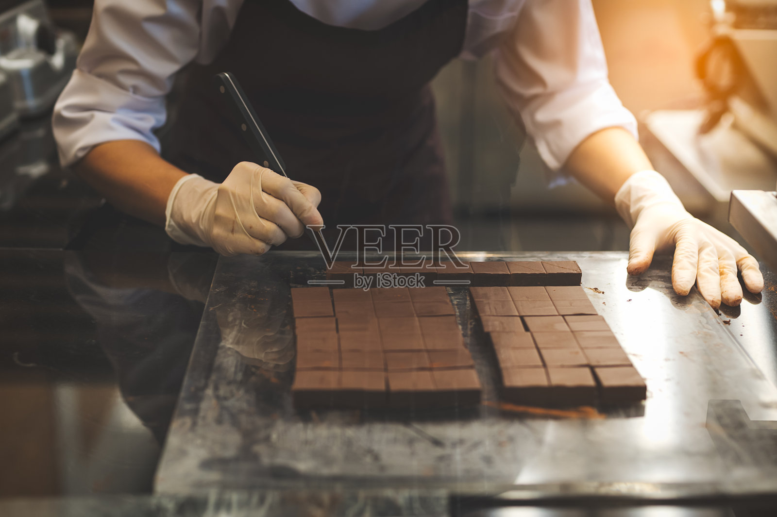 厨师在厨房切自制巧克力。照片摄影图片