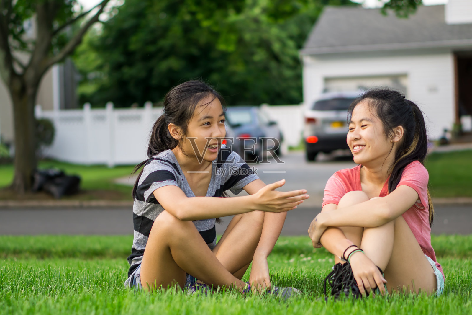 两个亚洲女孩坐在前门的草坪上照片摄影图片