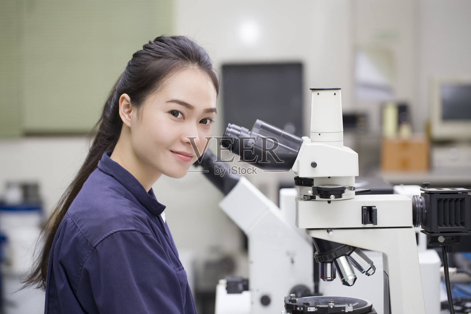 在实验室里用显微镜观察的女科学家照片摄影图片