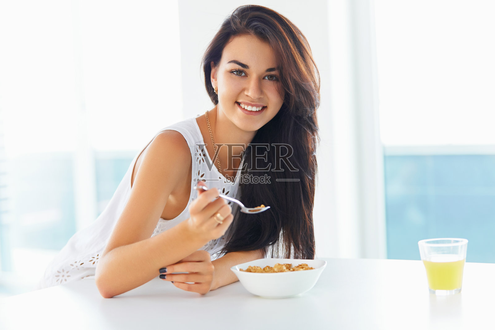 女人一边吃着麦片，一边对着镜头微笑照片摄影图片