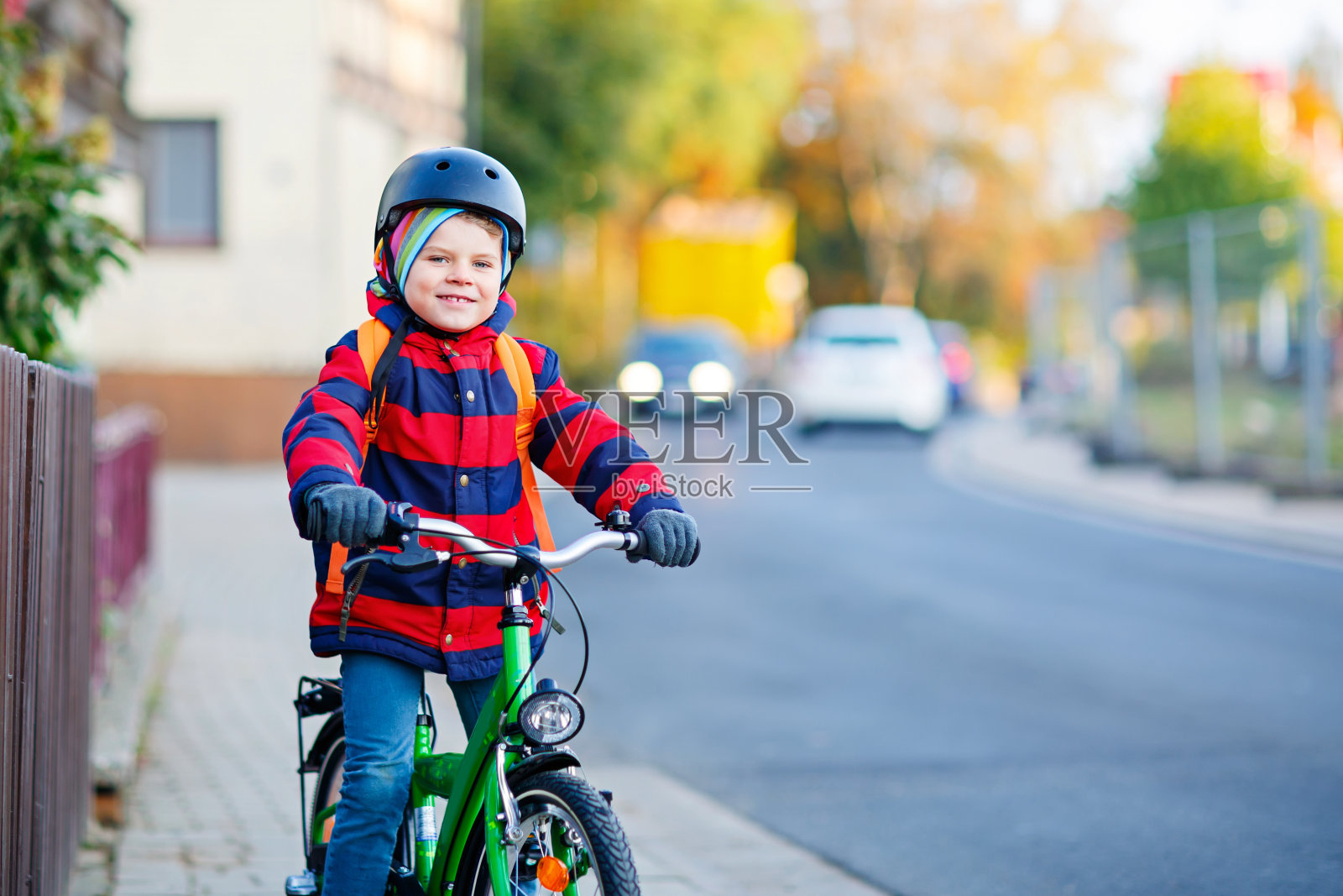 戴着头盔的小男孩骑着自行车穿过城市照片摄影图片