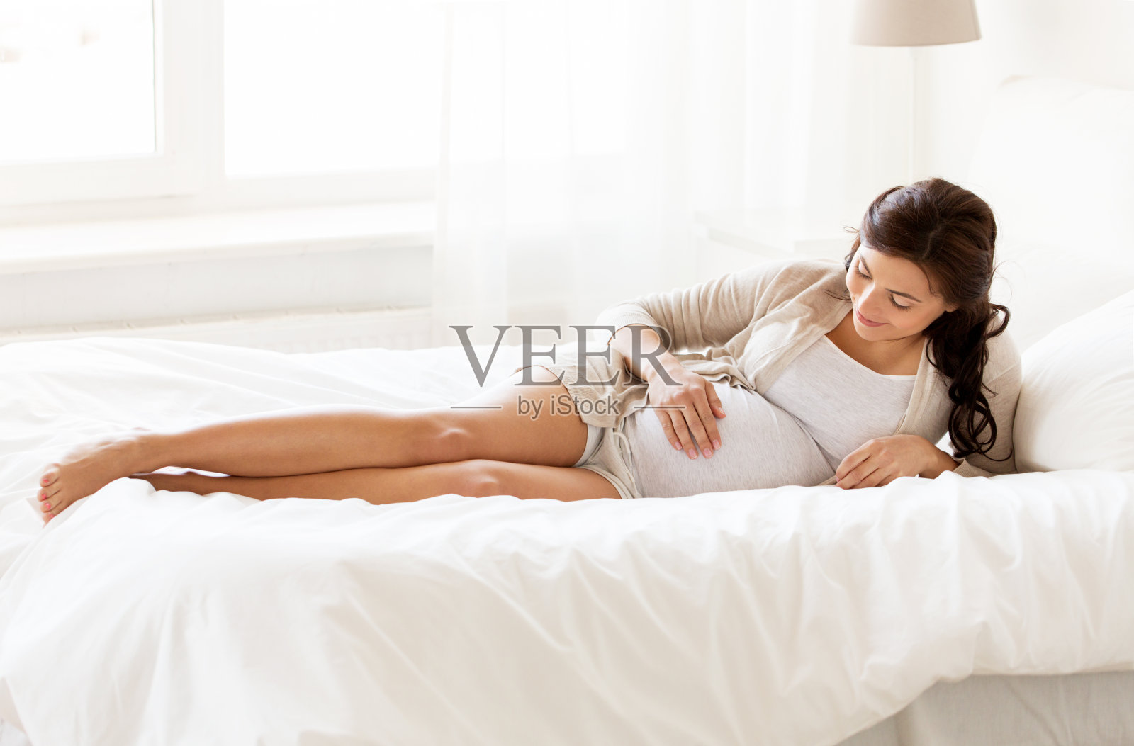 幸福的孕妇躺在家里的床上照片摄影图片
