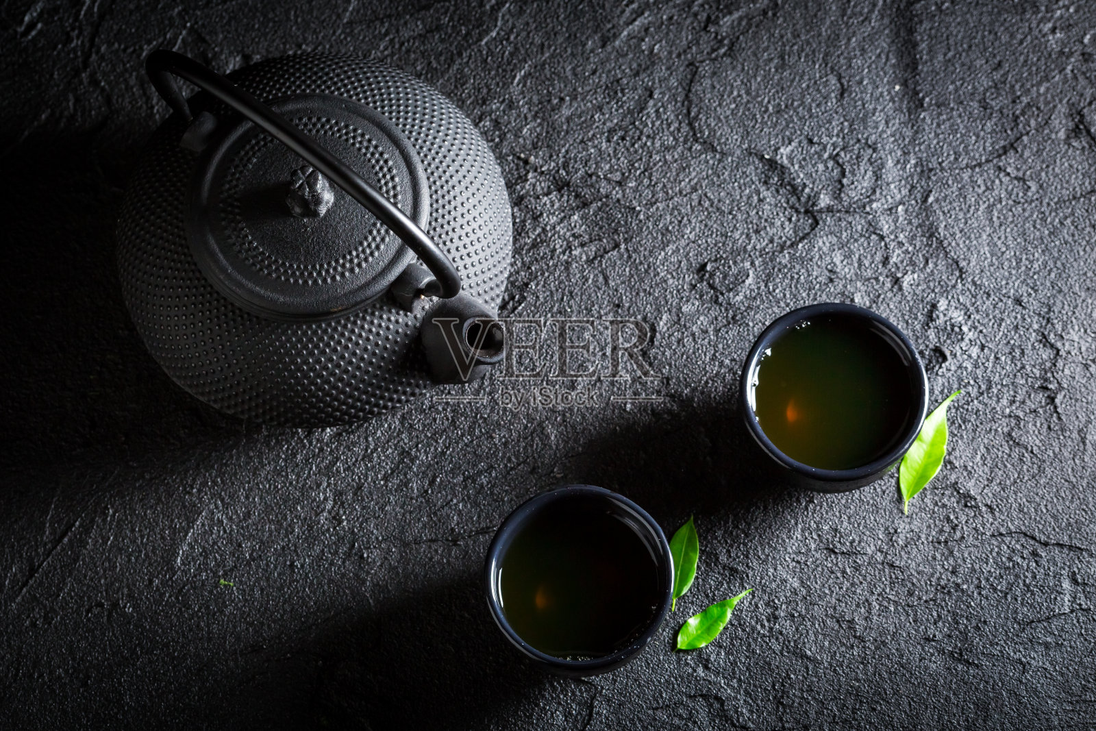 香喷喷的绿茶，用茶壶和茶杯泡在黑岩上照片摄影图片
