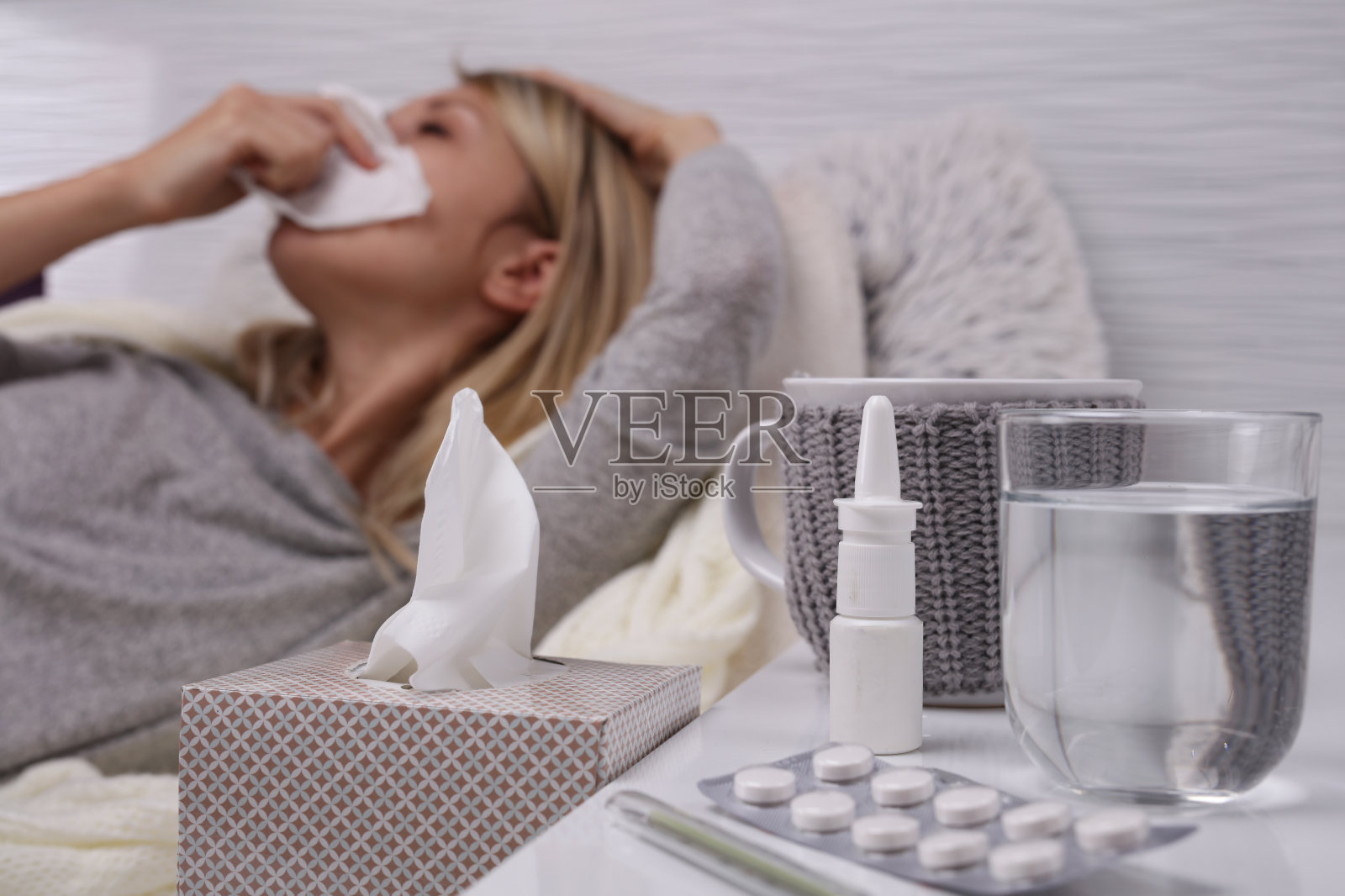 女人感冒了，流鼻涕，选择性地盯着纸巾盒。照片摄影图片