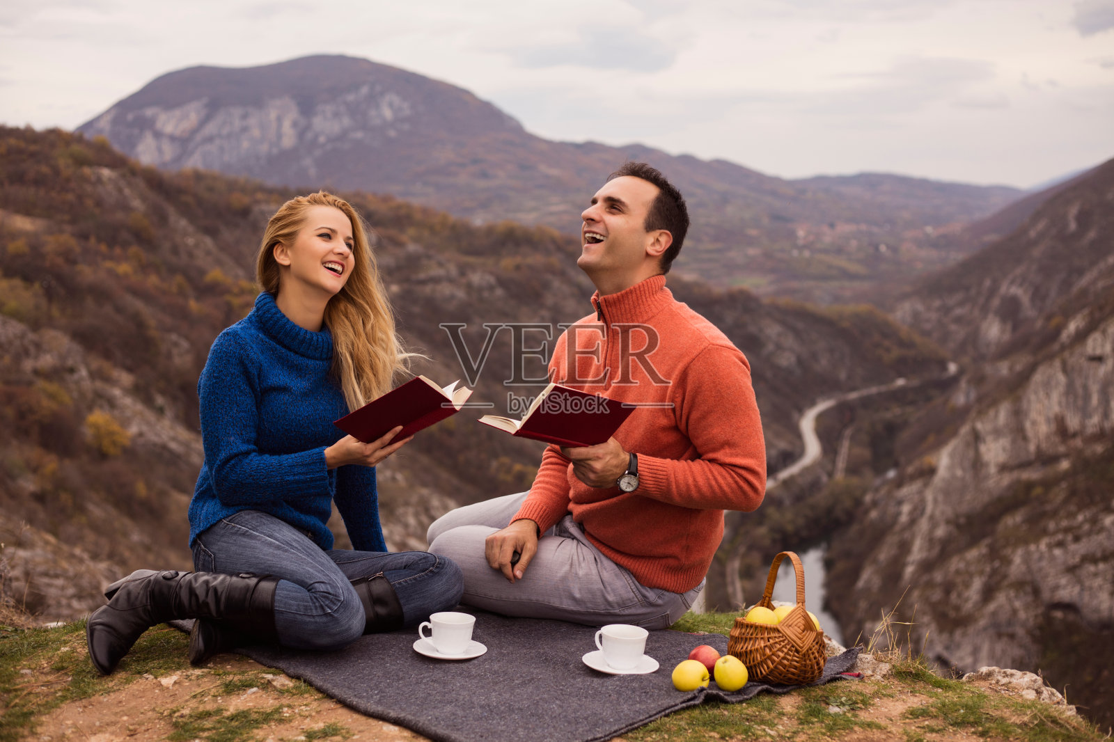快乐的情侣在野餐上读一本书和微笑。照片摄影图片