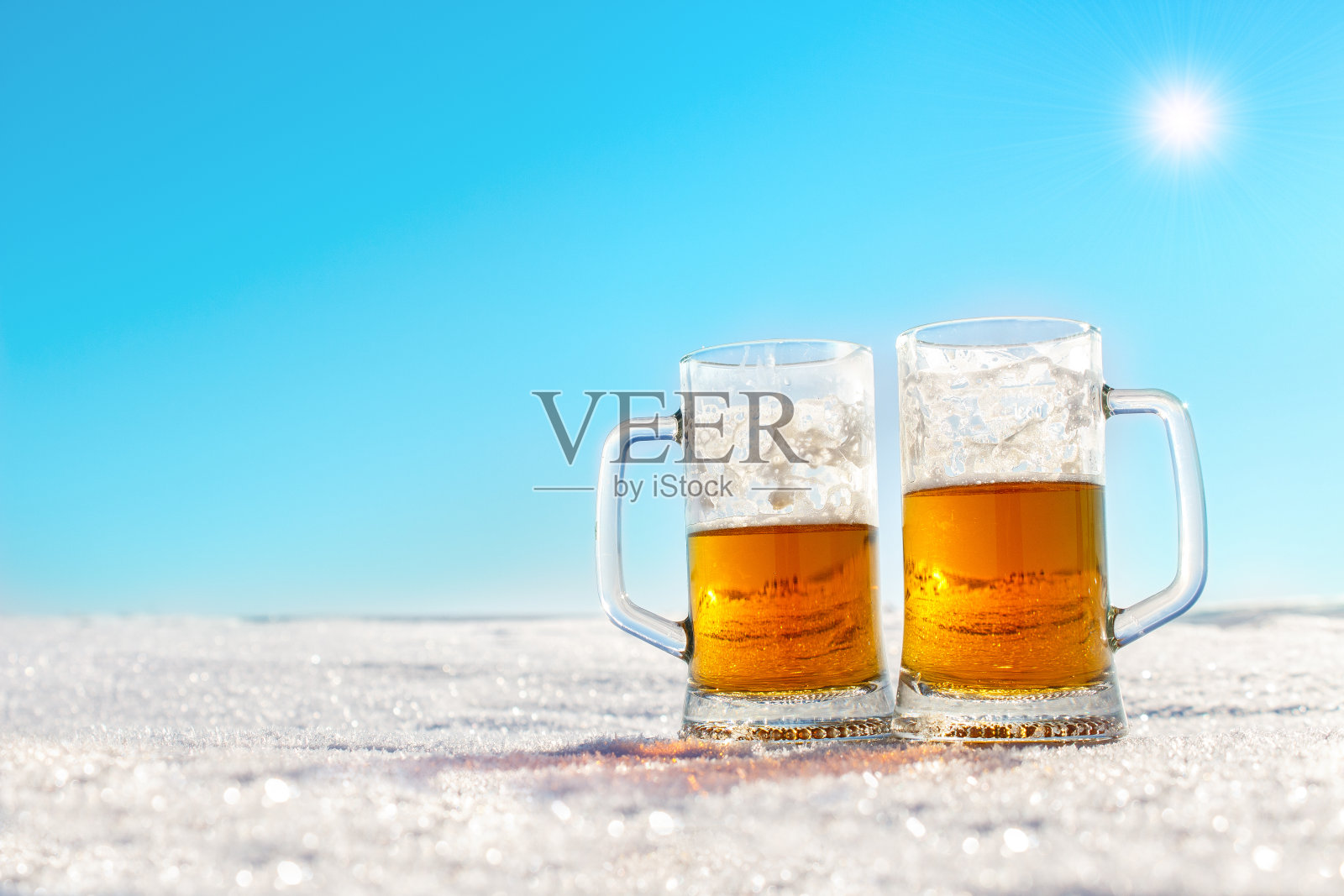 两杯冰镇啤酒放在雪地上照片摄影图片