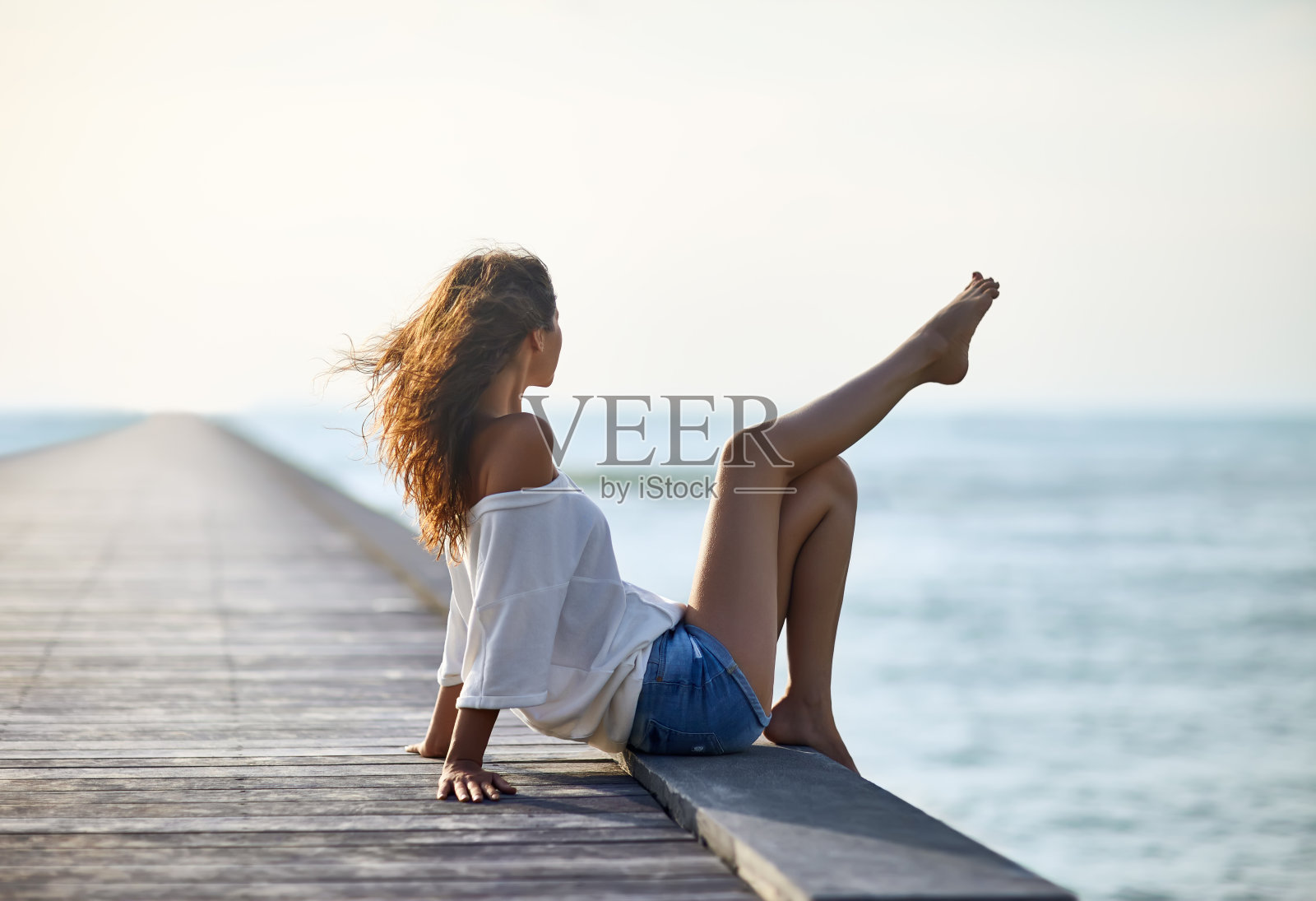 性感美丽的女人放松在码头与海景照片摄影图片