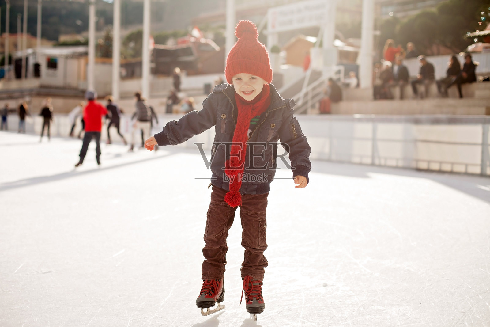 快乐的男孩戴着红帽子，白天溜冰照片摄影图片