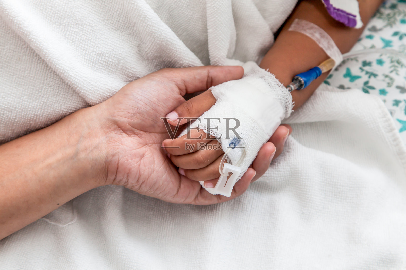 母亲握着有静脉输液的孩子的手照片摄影图片