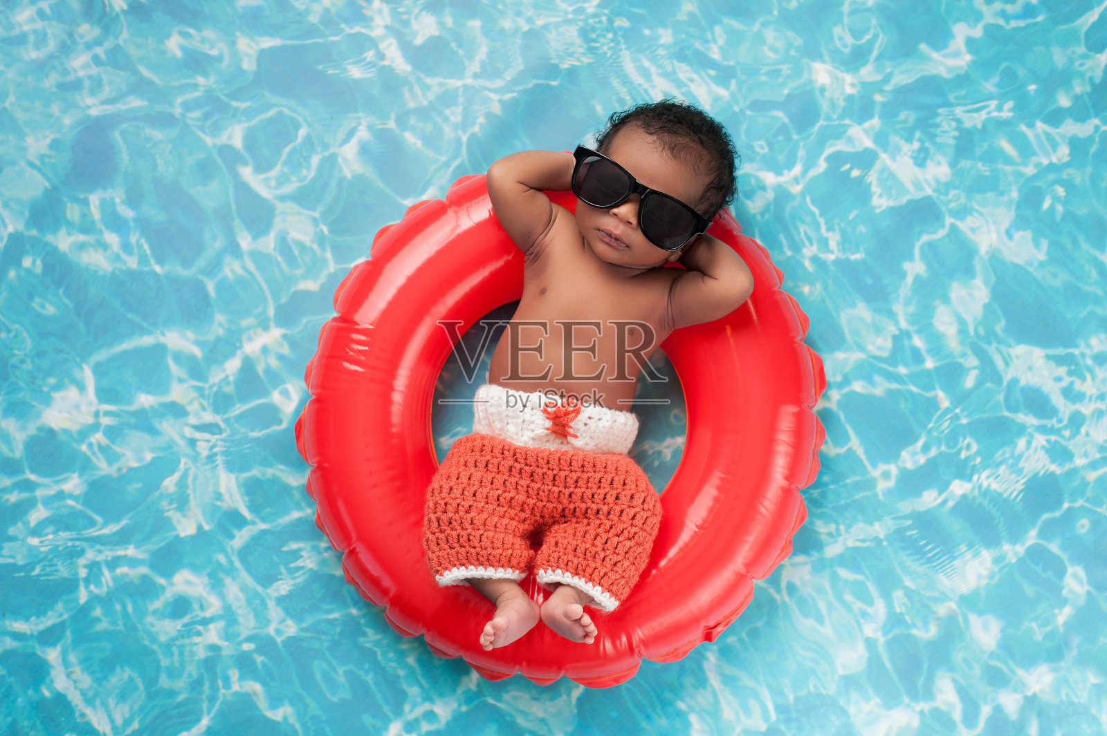 新生男婴漂浮在游泳圈上照片摄影图片