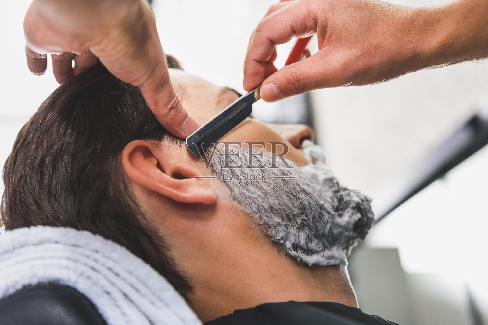 熟练的理发师用刀片刮胡须照片摄影图片