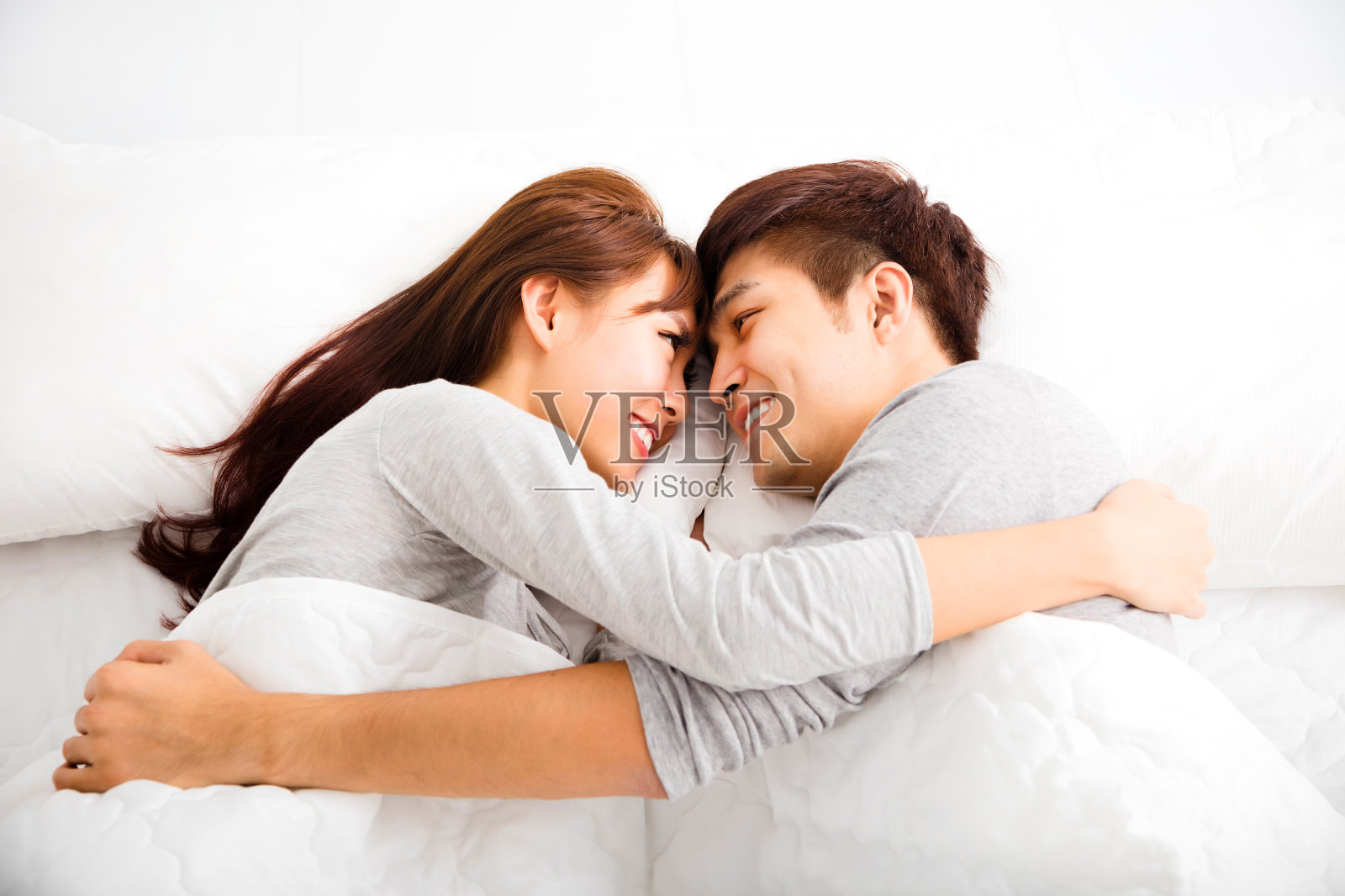 一对幸福可爱的年轻夫妇躺在床上照片摄影图片