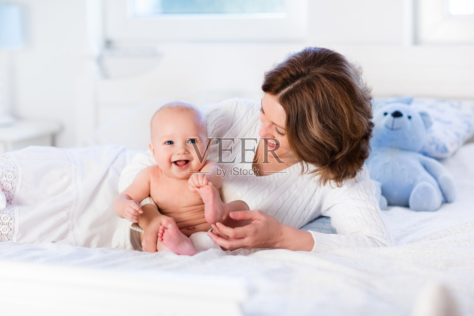 可爱的妈妈和宝宝在白色的床上照片摄影图片