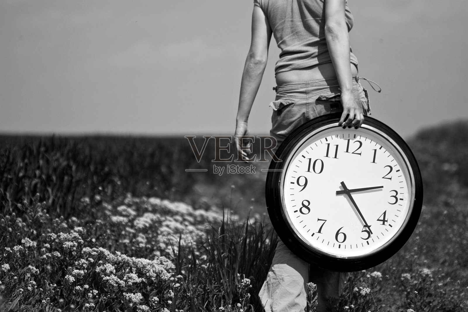 一个年轻女子背着一个大钟在田野上照片摄影图片