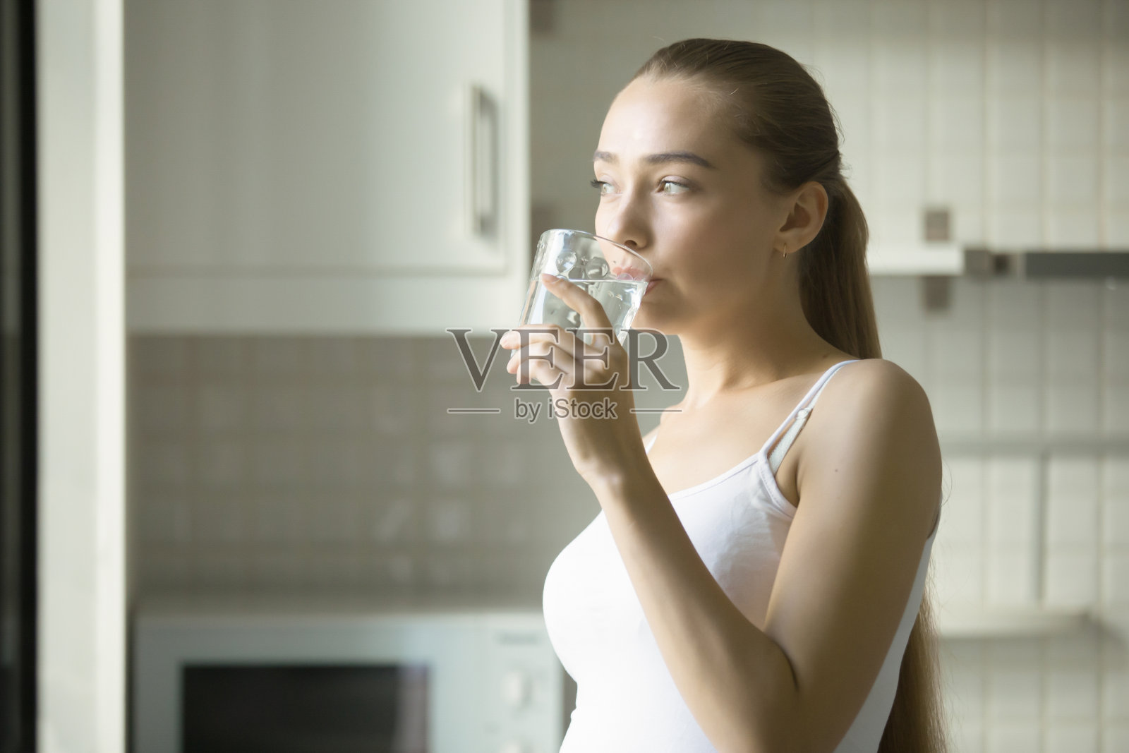 一个年轻迷人的女孩喝水的肖像照片摄影图片