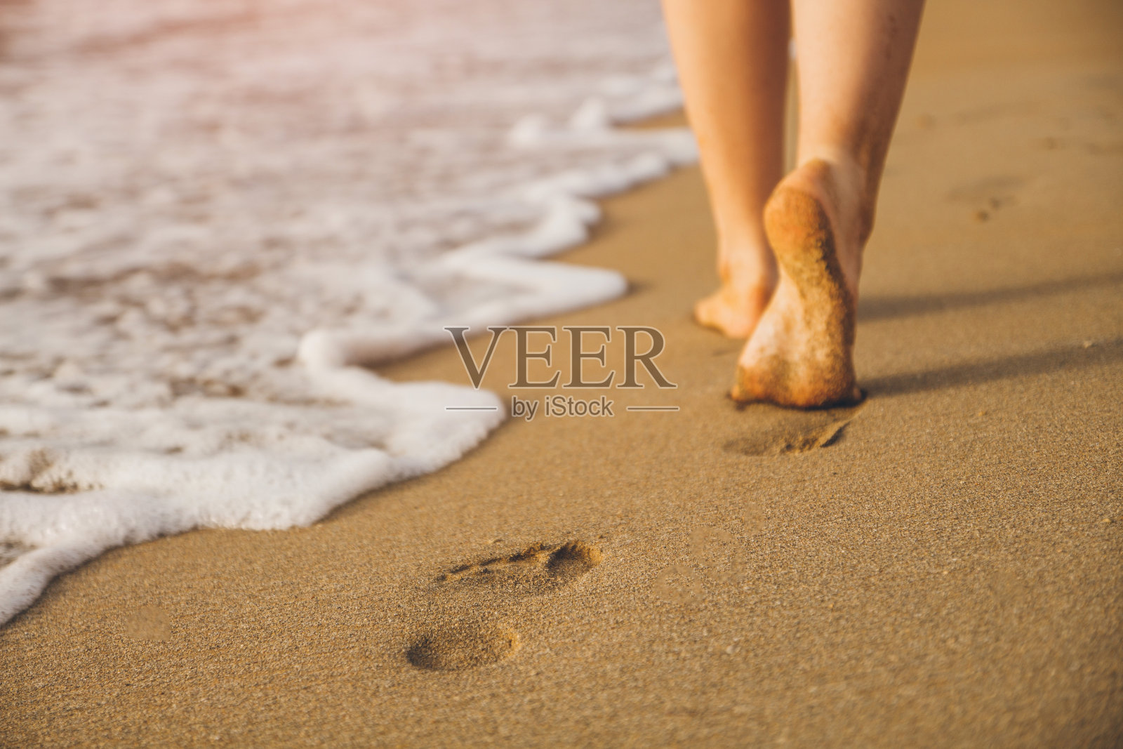女人走在沙滩上，在沙滩上留下脚印照片摄影图片