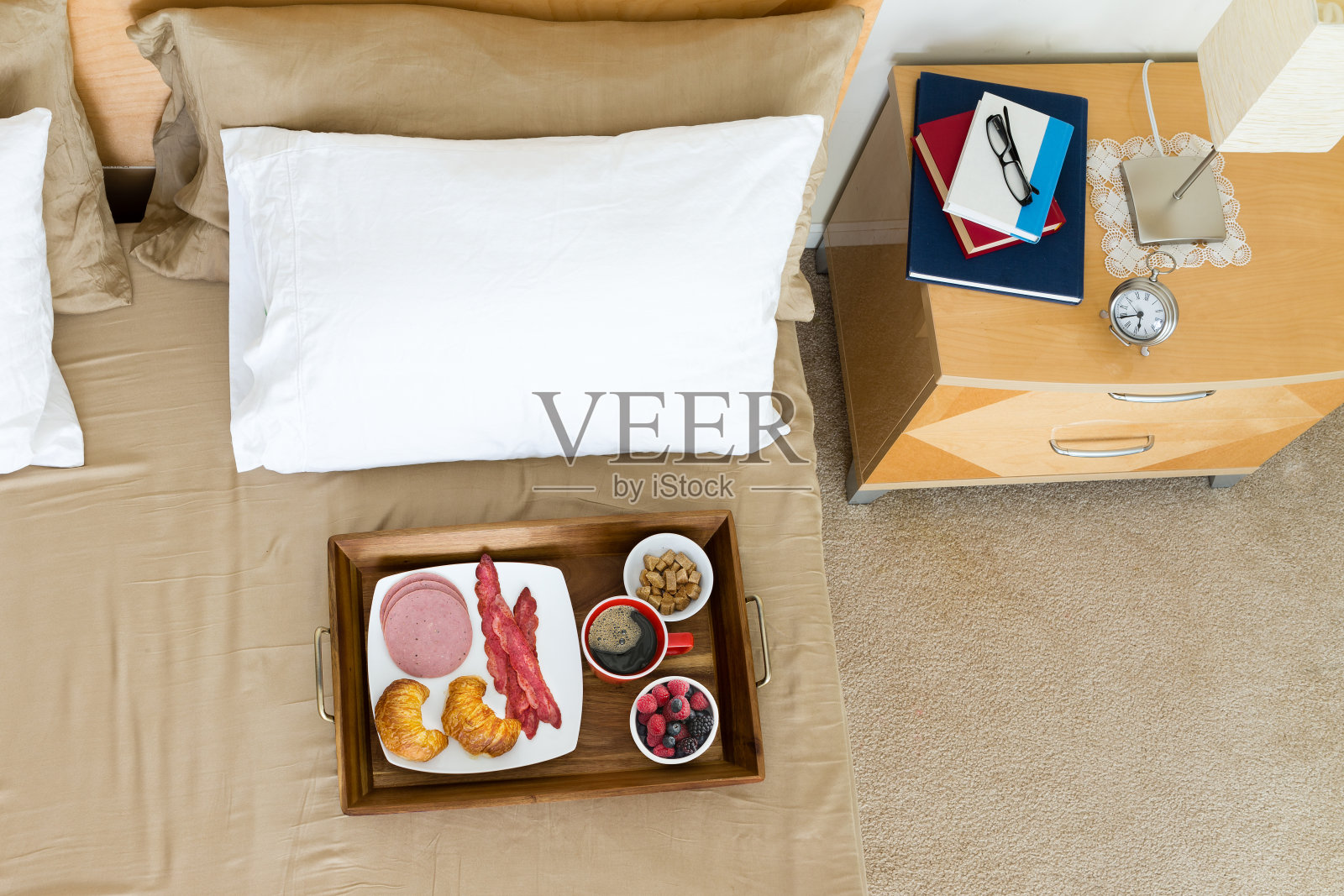 早餐放在床上，托盘放在床头柜旁边照片摄影图片