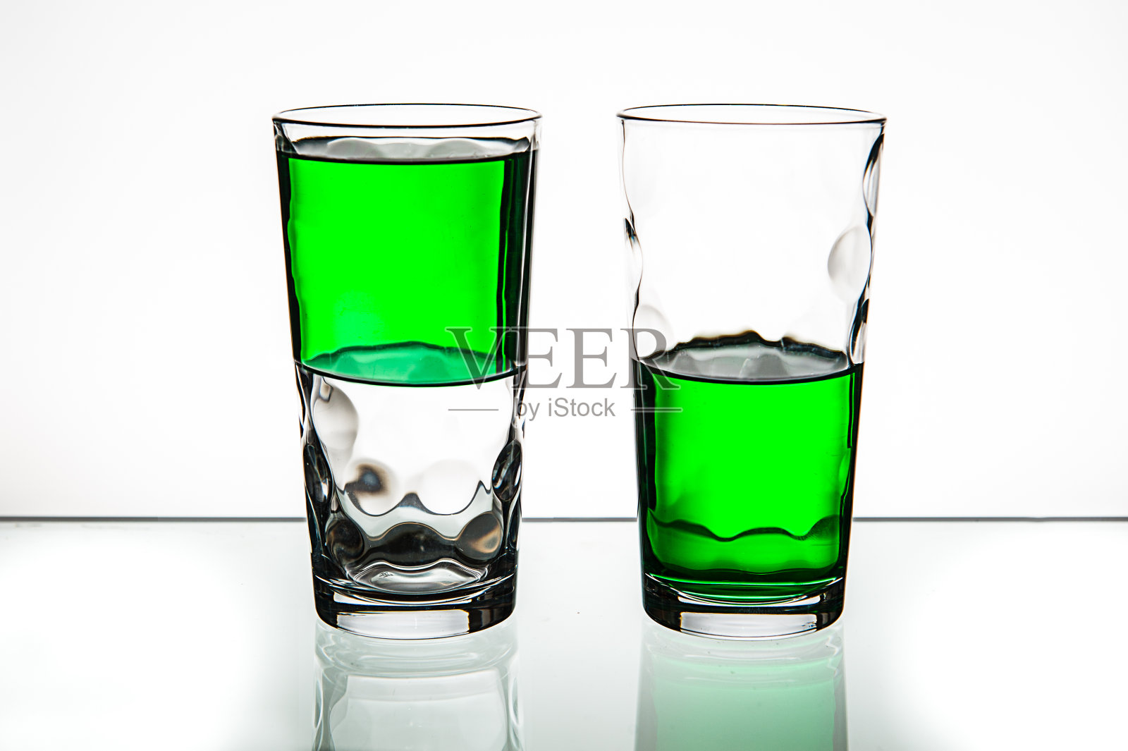 两杯，都是半满的绿色液体。照片摄影图片
