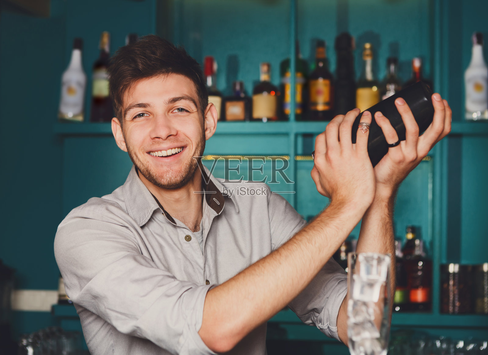 年轻英俊的酒保在酒吧摇晃和调酒鸡尾酒照片摄影图片
