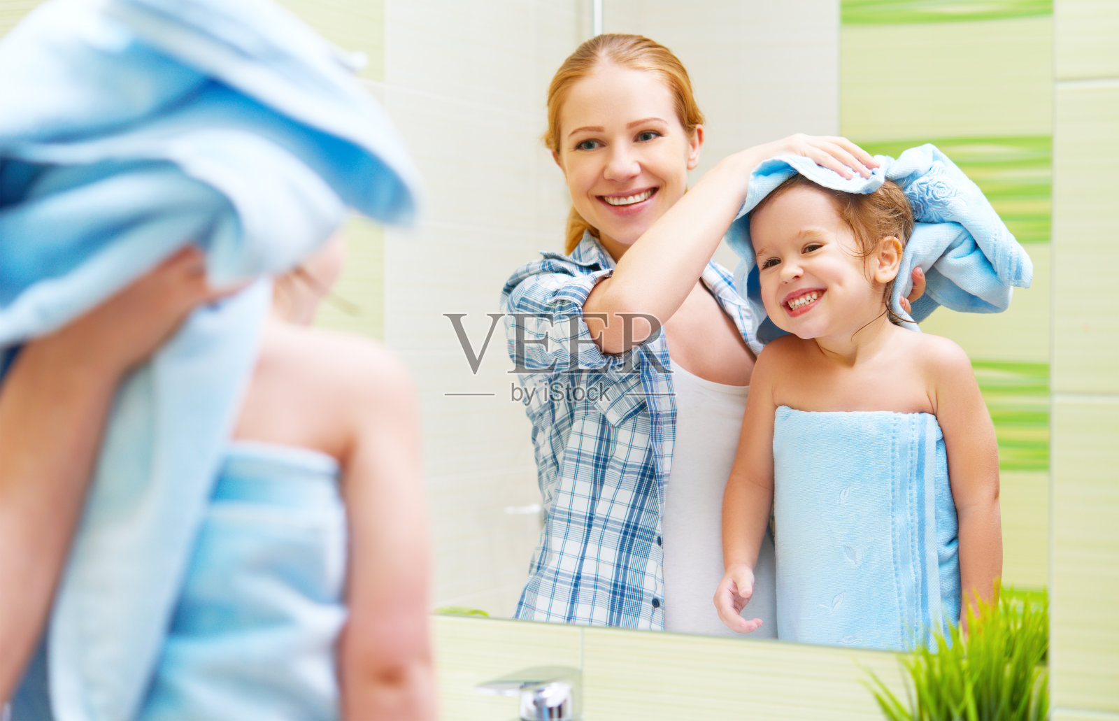家庭浴室。母亲用毛巾擦干了孩子的头发照片摄影图片