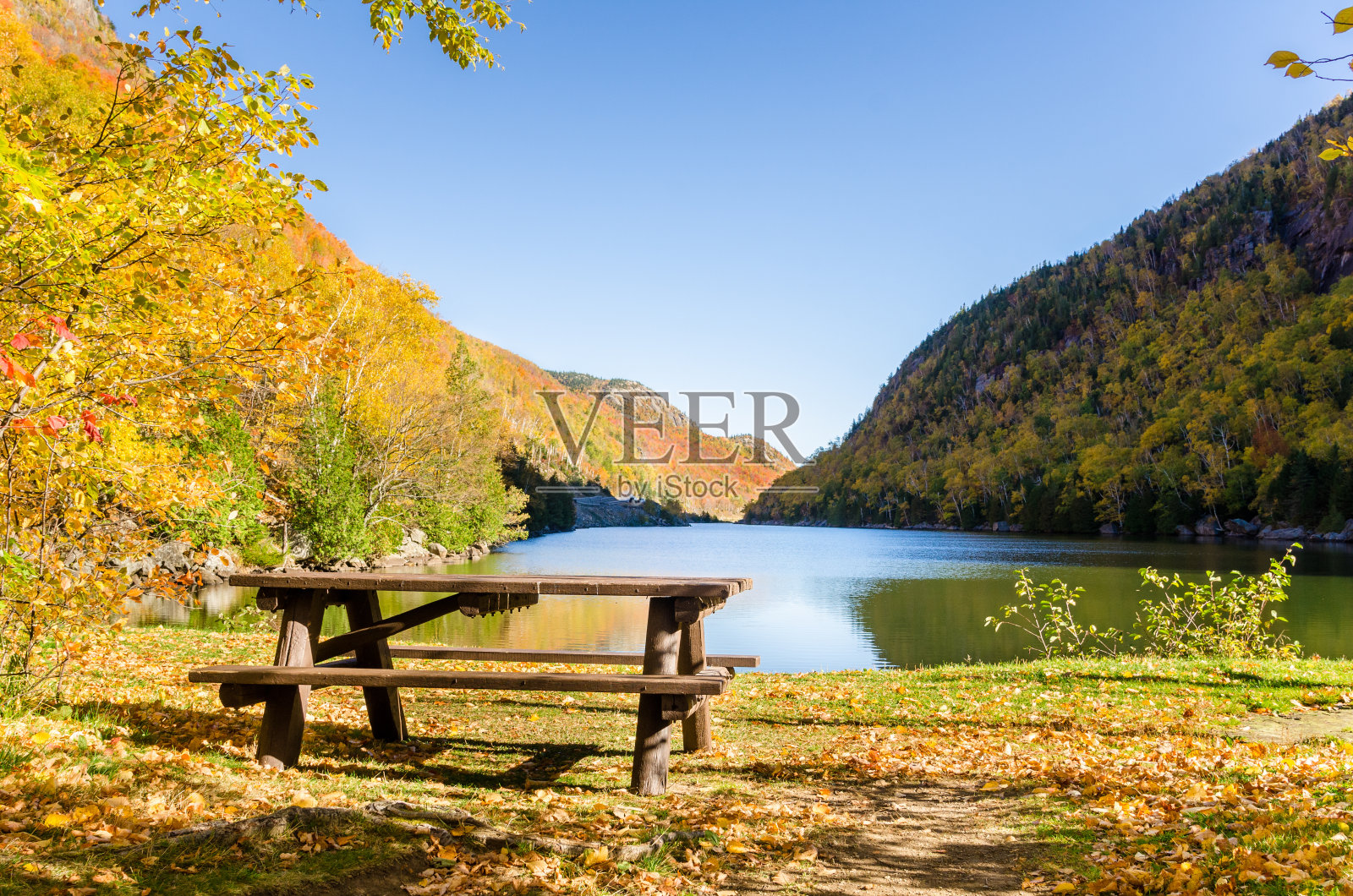 一个晴朗的秋日，山湖上的空野餐桌照片摄影图片