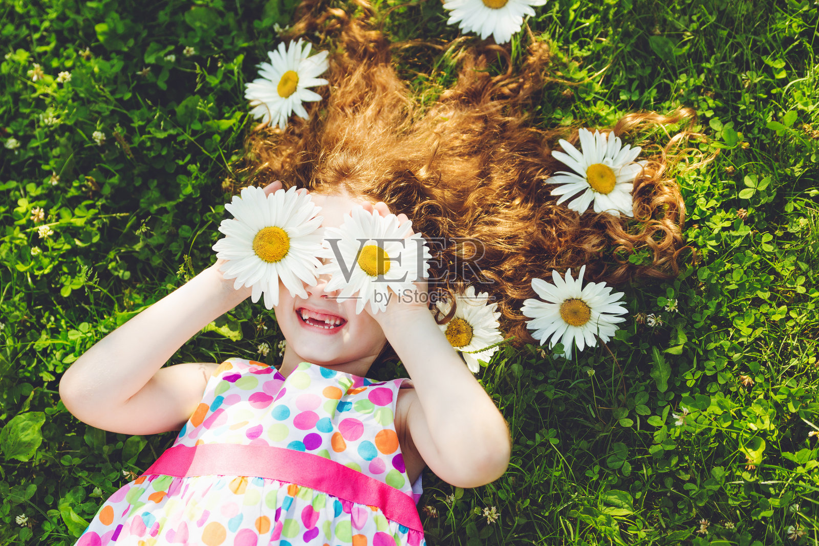 雏菊眼的孩子躺在绿草地上。照片摄影图片