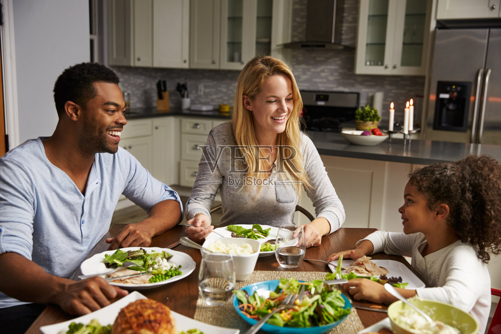 女孩和她的混血父母在厨房用餐照片摄影图片