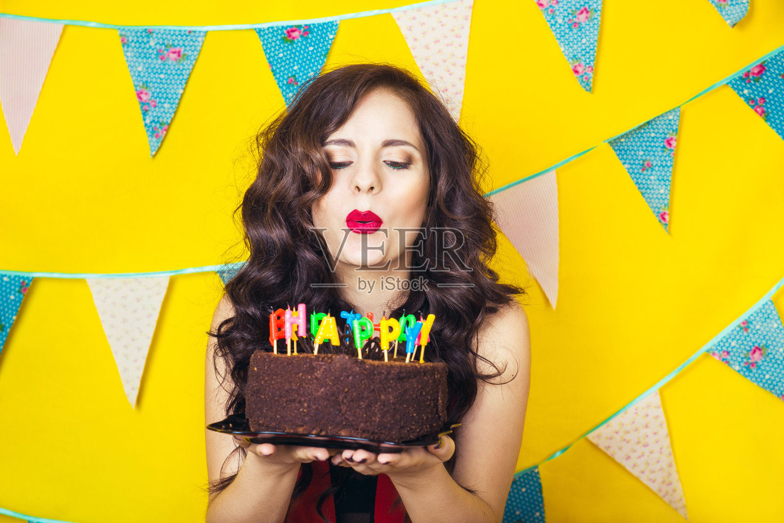 美丽的白人女孩在蛋糕上吹蜡烛。庆祝活动和聚会照片摄影图片