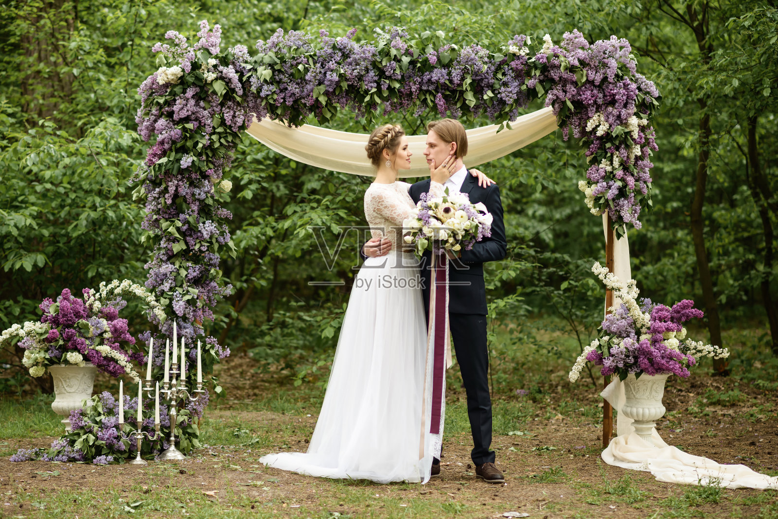 新郎新娘在紫丁香的拱门旁照片摄影图片