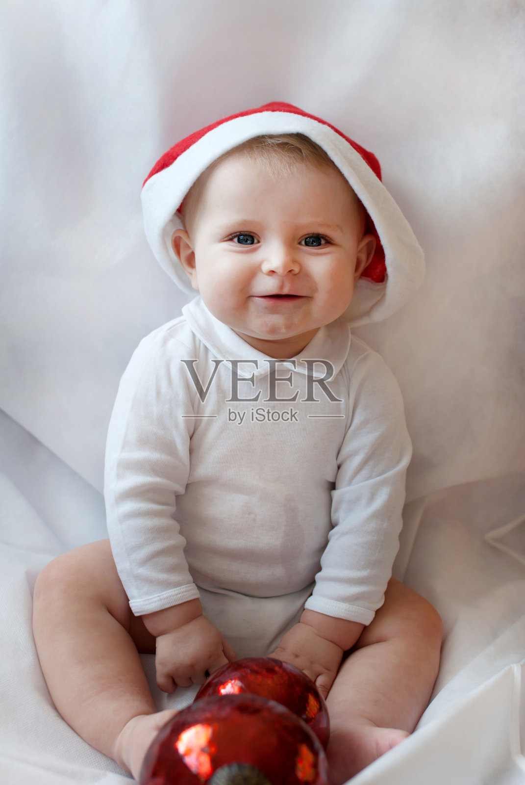 白色背景上戴着圣诞帽和球的男婴照片摄影图片