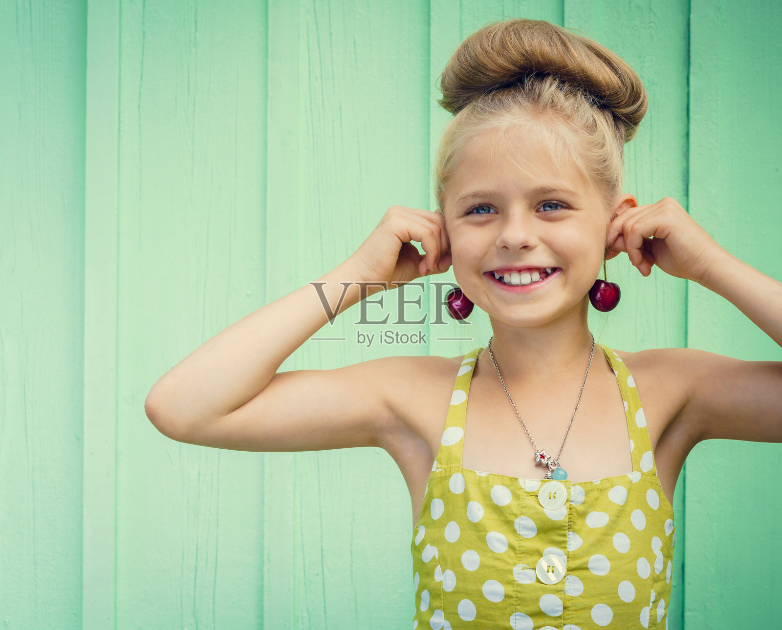 美丽的女孩拿着樱桃作为耳环风格的Rockabilly。照片摄影图片