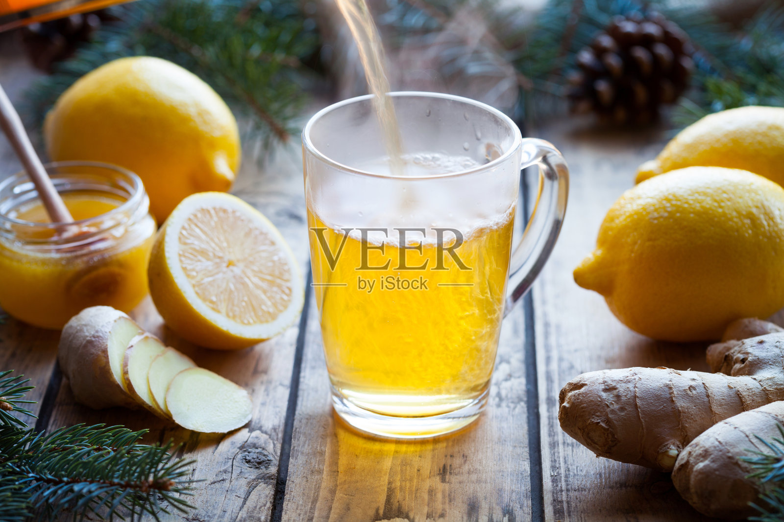 维生素绿茶与生姜，柠檬和蜂蜜倒在一个杯子上蒸汽古董木桌。照片摄影图片