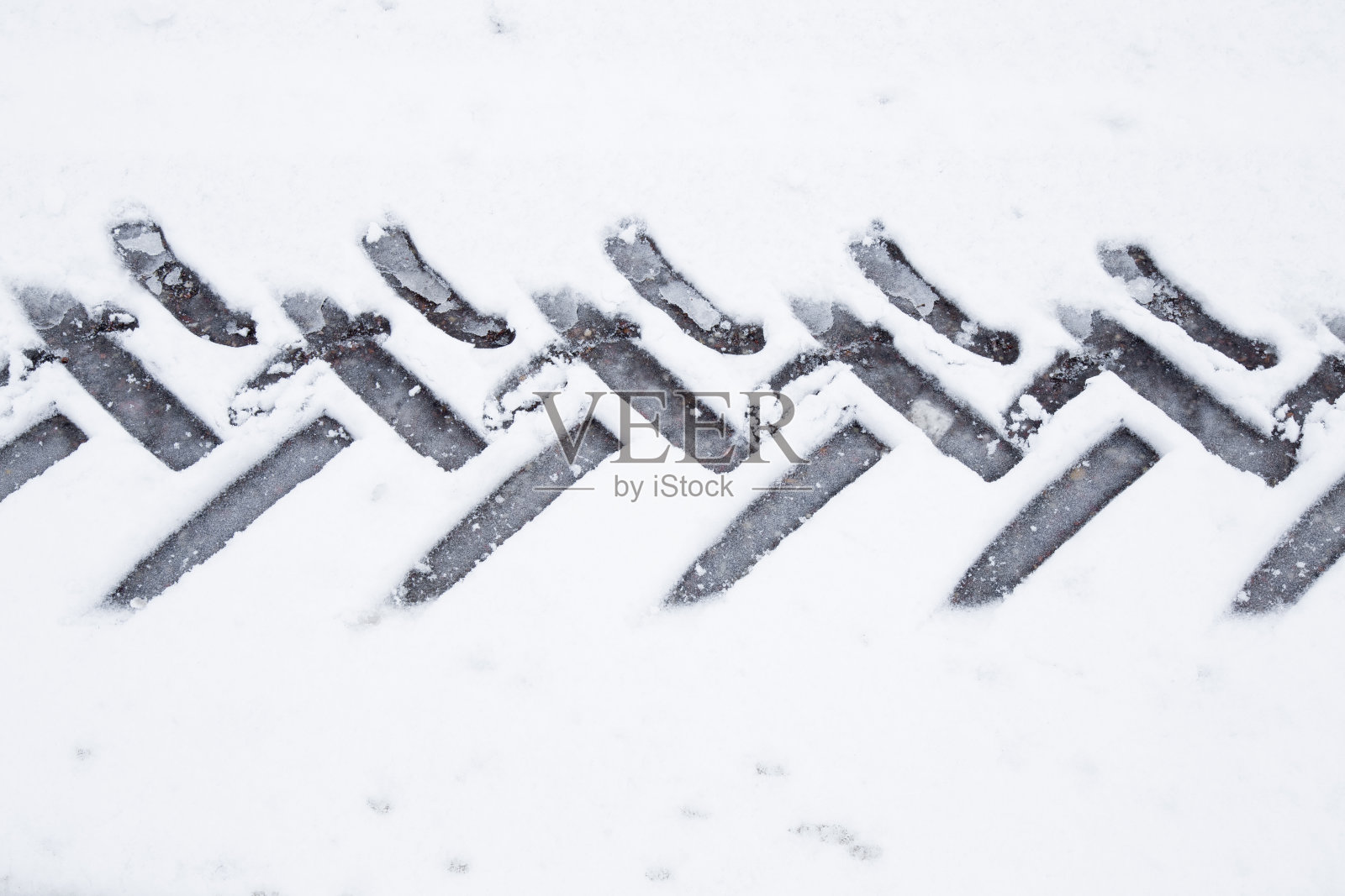 拖拉机轮胎印在湿软的雪地上。湿滑的道路。照片摄影图片