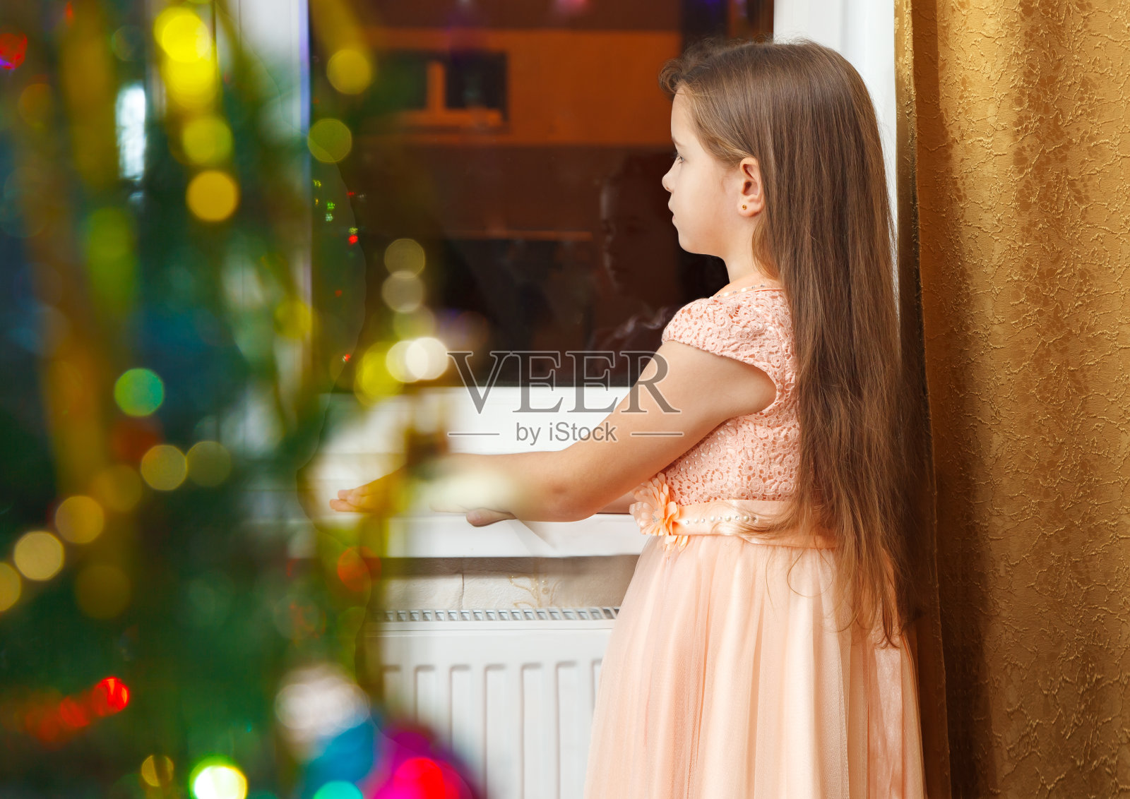 圣诞节时站在窗前的小女孩照片摄影图片