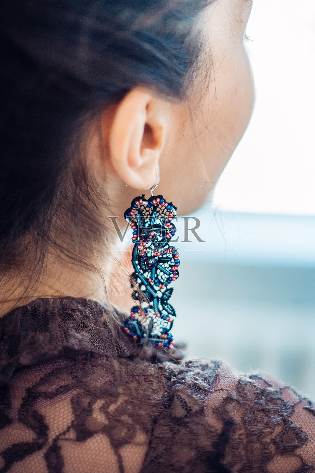 一个年轻女子的耳朵上的手工耳环。照片摄影图片