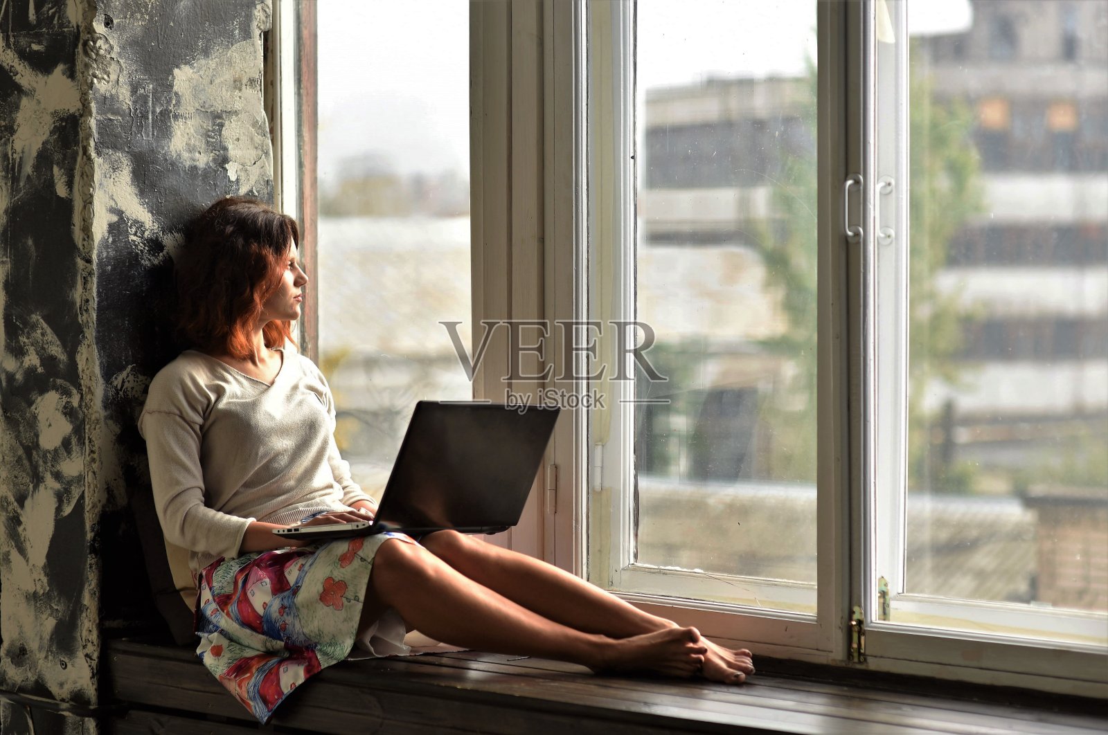 窗台上坐着个手提电脑的美女照片摄影图片
