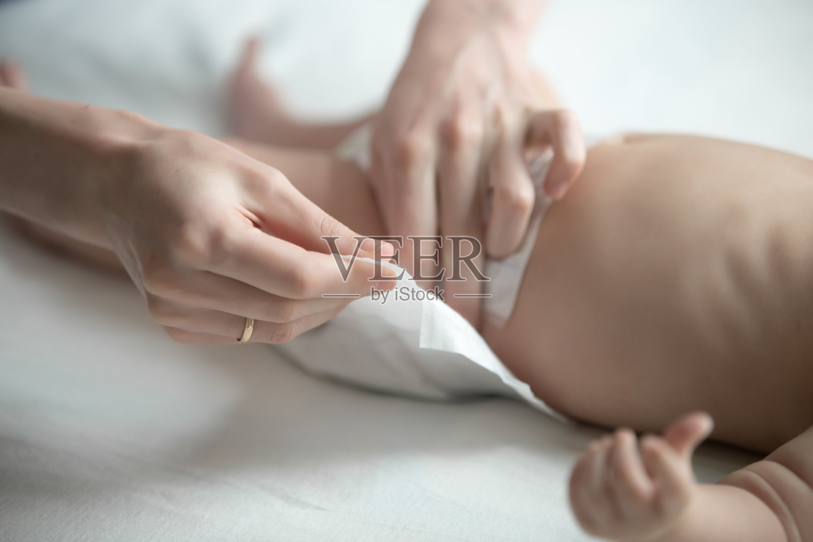 女人的手正在给躺着的新生儿换尿布照片摄影图片