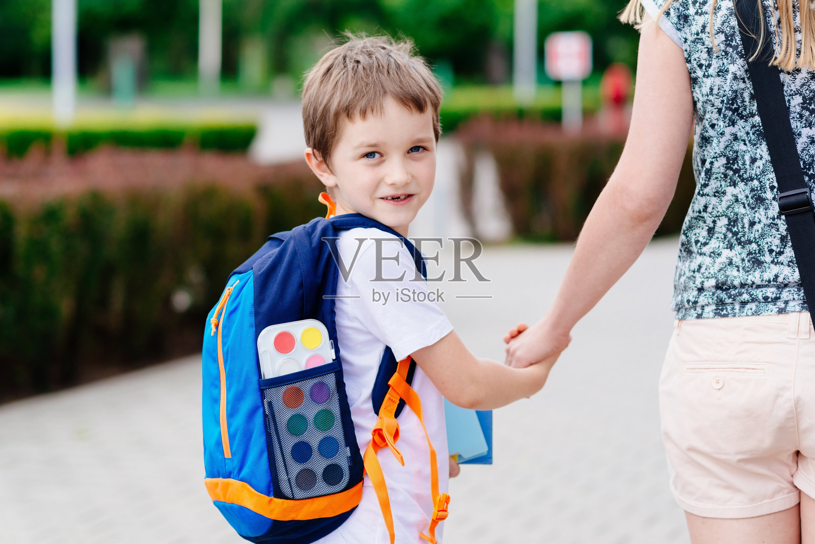 男孩和他妈妈在上学的路上。照片摄影图片
